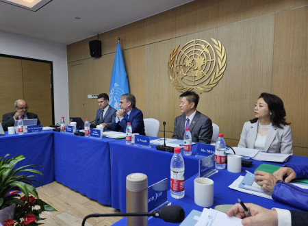 Udeleženci zasedanja v dvorani z logotipom Združenih narodov na steni