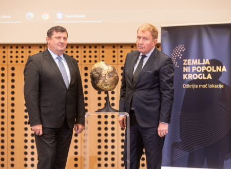 Tomaž Petek in mag. Miran Gajšek stojita na odru, v ospredju maketa geoida Zemlje, ki predstavlja enega izmed sloganov konference - zemlja ni popolna krogla