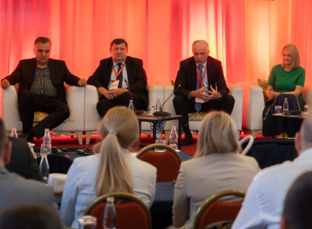 Panelisti sedijo na odru, pred publiko v dvorani
