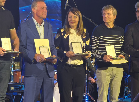 na sliki stoji naša predstavnica in še štirje moški, vsi s plaketami in diplomami v rokah, vsi stojijo na odru