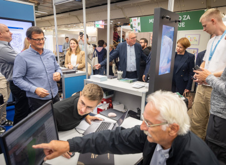 Obiskovalec sedi pred zaslonom in pregleduje podatke o svoji nepremičnini. V ozadju je tudi minister za naravne vire in prostor in drugi obiskovalci.
