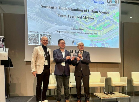 Trije moški stojijo pred projekcijskim platnom in držijo nagrado, eden izmed njih je nagrajenec za doktorsko nalogo.