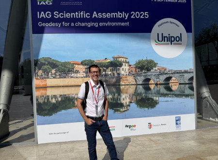 Moški stoji pred velikim plakatom dogodka pred vhodom v kongresni center.