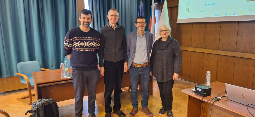 Na sliki stojijo štiri osebe, trije moški in ena ženska, ki predstavljajo staro in novo predsedstvo Slovenskega združenja za geodezijo in geofiziko.