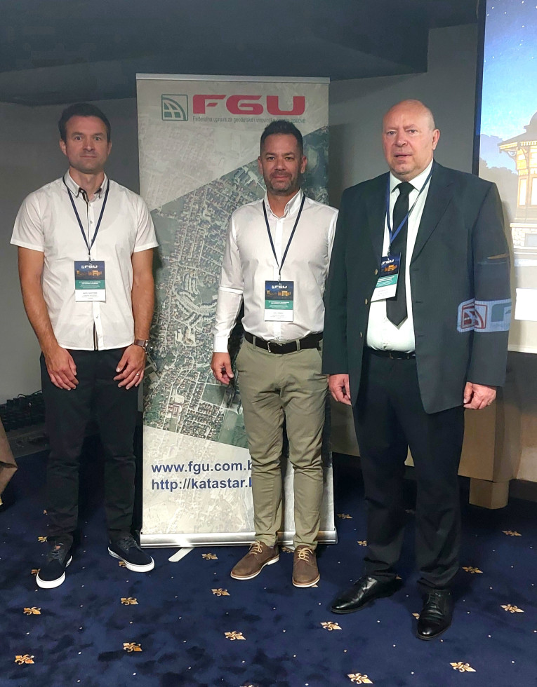 Trije moški stojijo pred panojem Federalne uprave za geodetske in imovinsko-pravne poslove na konferenci v Sarajevu.