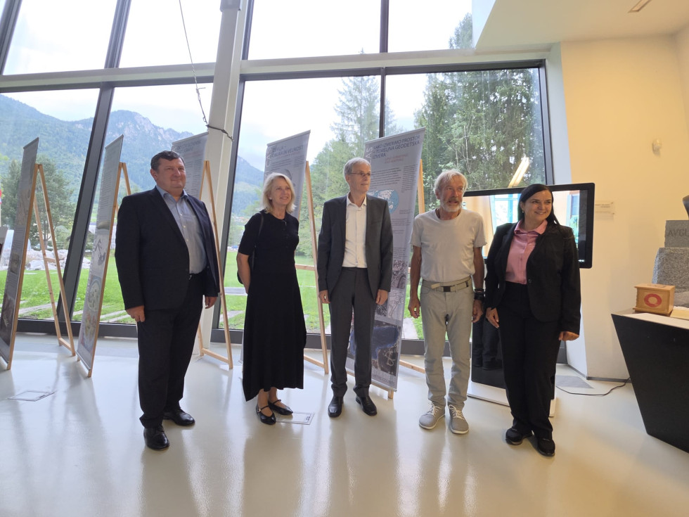 Skupina treh moških in dveh žensk stoji v razstavnem prostoru Slovenskega planinskega muzeja. V ozadju so razstavni panoji in velika okna s pogledom na okolico.