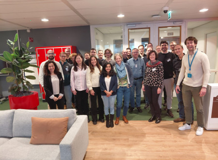 Skupina moških in žensk stoji nasmejana v notranjem prostoru pred vrati sejnih sob.