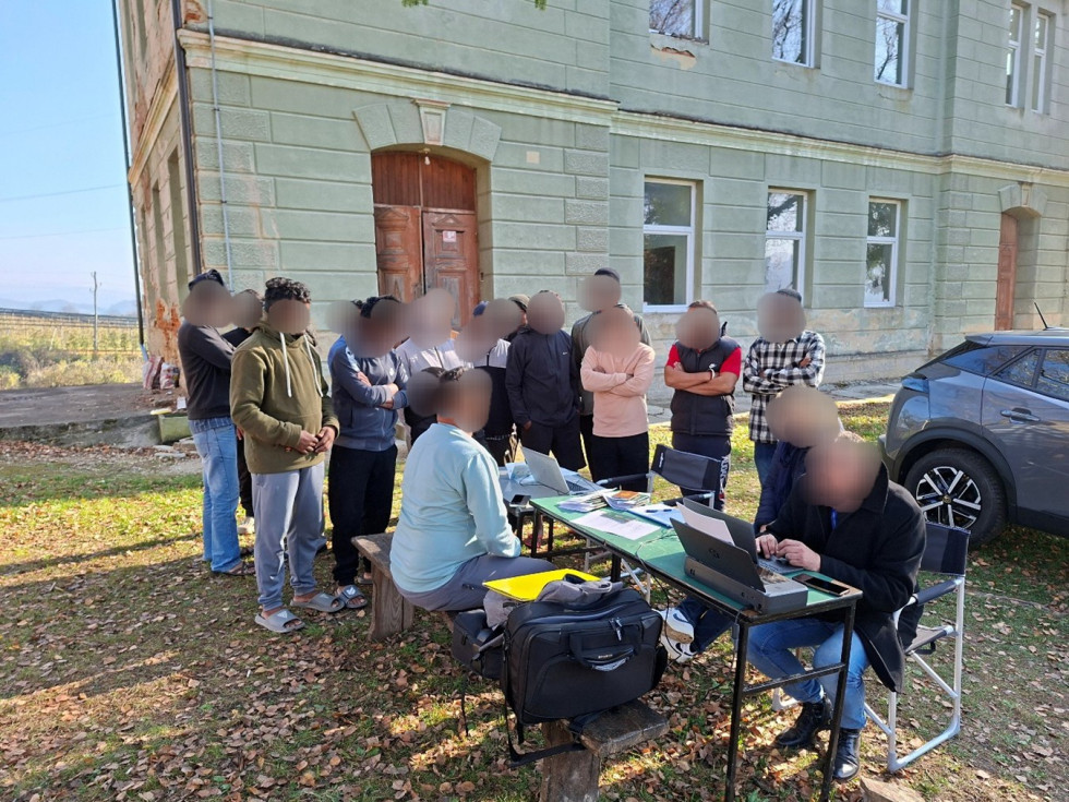 skupina moških delavcev stoji ob mizi pri inšpektorju