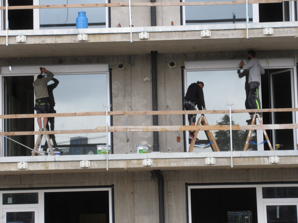 trije delavci na balkonu montirajo okna