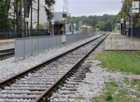 nezavarovan prehod čez želežniško progo, v ozadju jeklena varnostna ograja med  dvema želežniškima progama