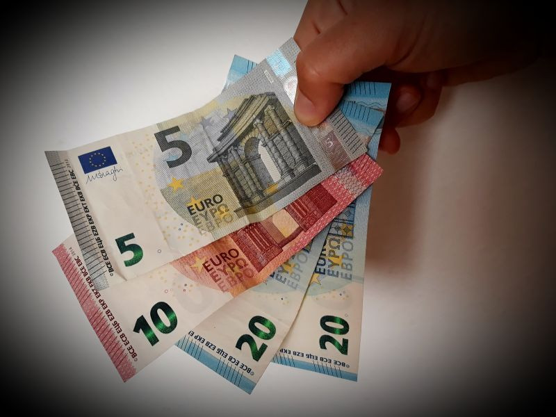 Roka, ki drži bankovce za 5, 10 in dvakrat po 20 evrov.