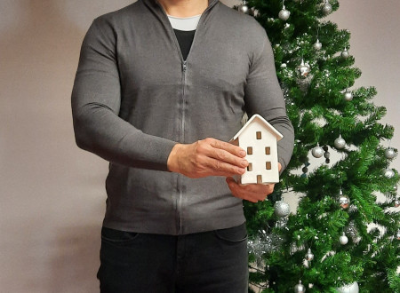 Direktor zoran Remic ob božičnem drevesu drži glineno hišico