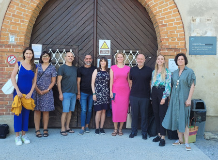 Domači in tuji udeleženci srečanja na skupinski fotografiji, v ozadju vrata ženskega zapora na Igu