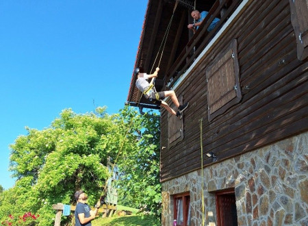 Plezanje in uporaba vrvne tehnike na koči, mladoletnik se spušča po objektu navzdol, varujejo ga drugi.