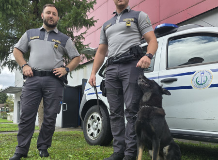 Pravosodna policista ob službenem vozilu, skupaj s psičko Kleo.
