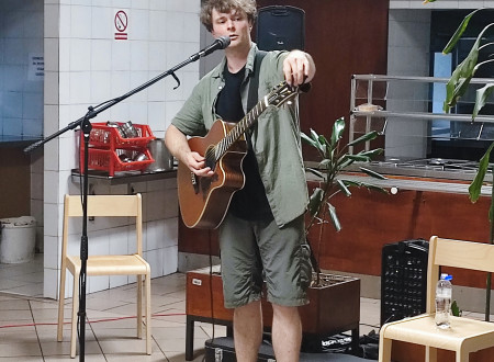 Kantavtor uglašuje kitaro, pred njim mikrofon