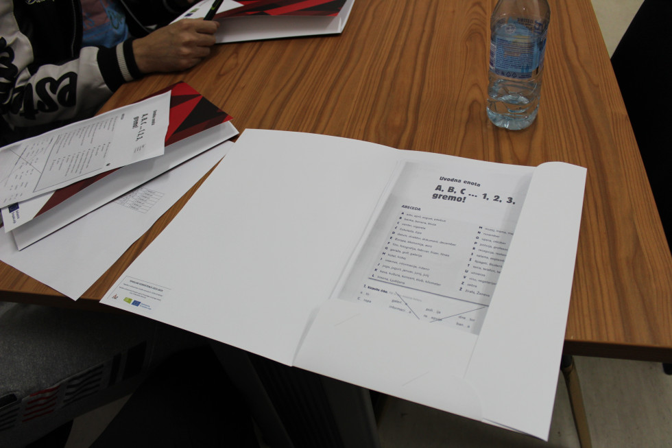 Na mizi je mapa v kateri je učno gradivo pri tečaju slovenskega jezika