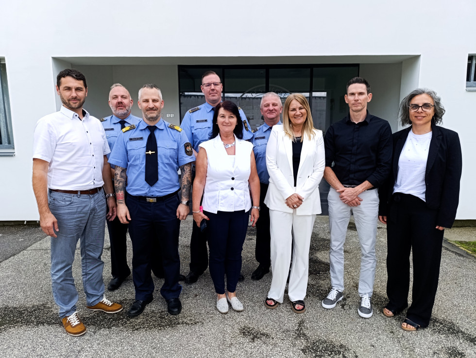 Na fotografiji so vsi člani obeh delegacij. Devet oseb. Slikani pred vhodom v enega od dveh zaporov, ki su ju obiskali.