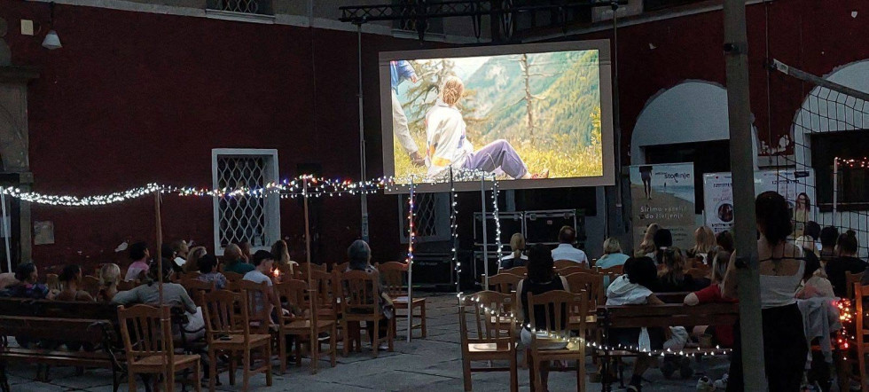 Zaprte osebe gledajo film na dvorišču zapora. Prizorišče je osvetljeno z lučkami, projekcija je v temi