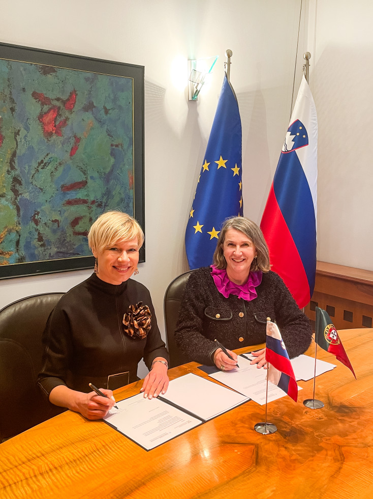 direktorica slovenskega urada mag. Karin Žvokelj in predsednica upravnega sveta portugalskega inštituta Ana Bandeira med podpisom načrta, se smehljata v kamero