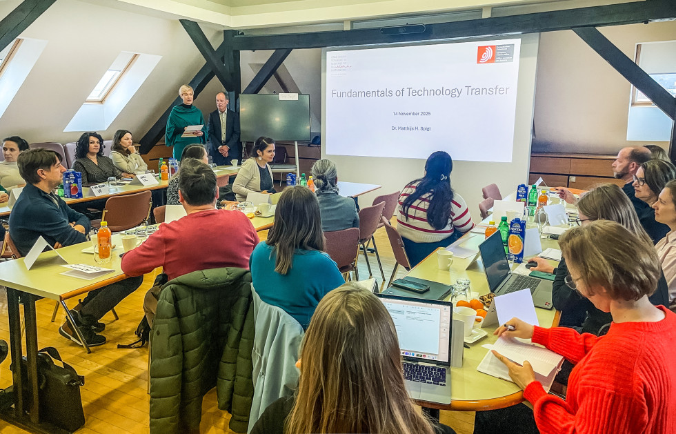 polna sejna soba slušateljev, na zaslonu projicirana predstavitev z naslovom predavanja