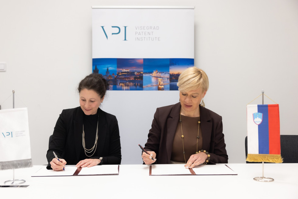 Two women sitting and signing documents.