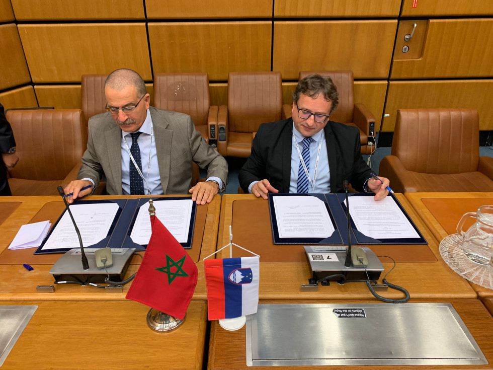 Za mizo direktorja upravnih organov Slovenije in Maroka, pred njima podpisni mapi ter slovenska in maroška zastava. 