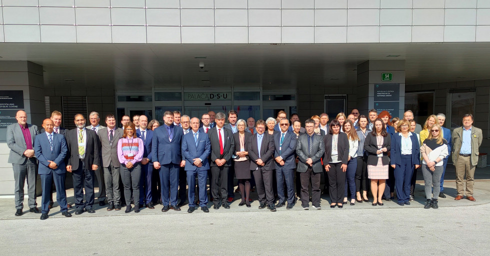 Skupinska fotografija vseh tujih in slovenskih udeležencev misije pred vhodom v stavbo s sedežem URSJV