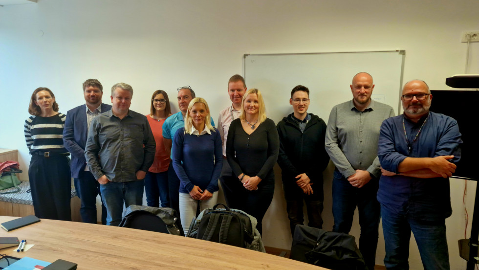 group photo of eleven members standing in front of the conference desk