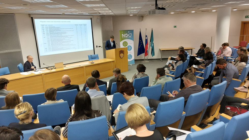 Udeleženci dogodka poslušajo moškega za govornico.