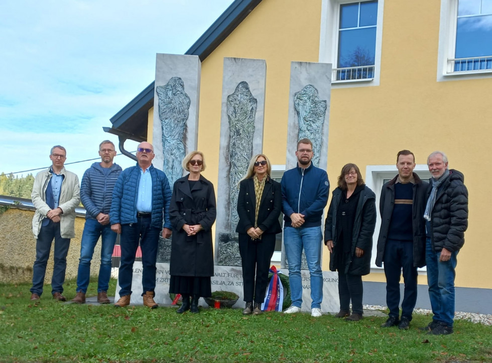 Skupinska fotografija udeležencev slovesnosti, ki stojijo pred pred spomeniki h katerim so položili vence