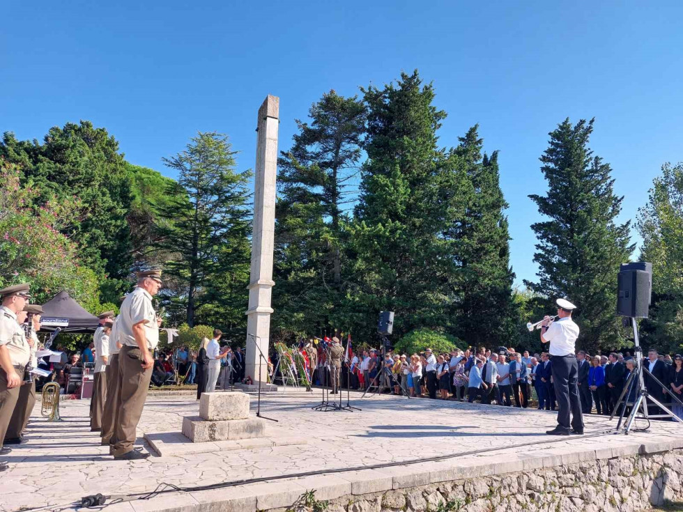 Udeleženci komemoracije stojijo ob ploščadi vojnega grobišča