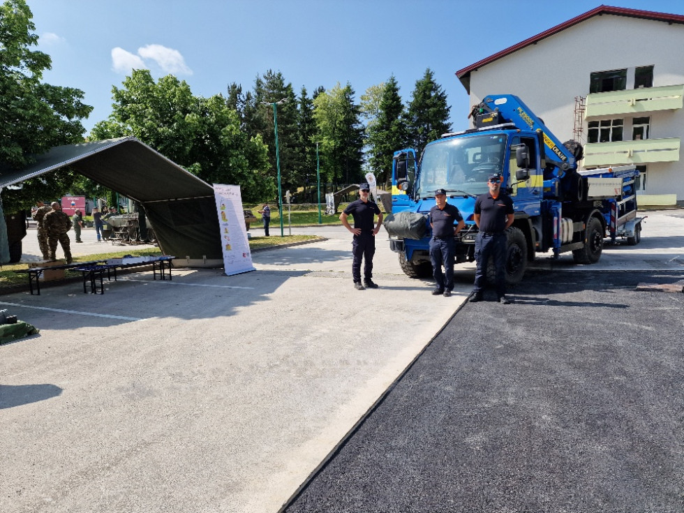 na Fotografiji sta dva pogodbena pripadnika CZ, enote za tehnično reševanje in predstavnik izpostave URSZR Postojna, v ozadju se vidi vozilo UNIMOG s črpalko za prečrpavanje večjih količin vode za tehnično reševanje.  