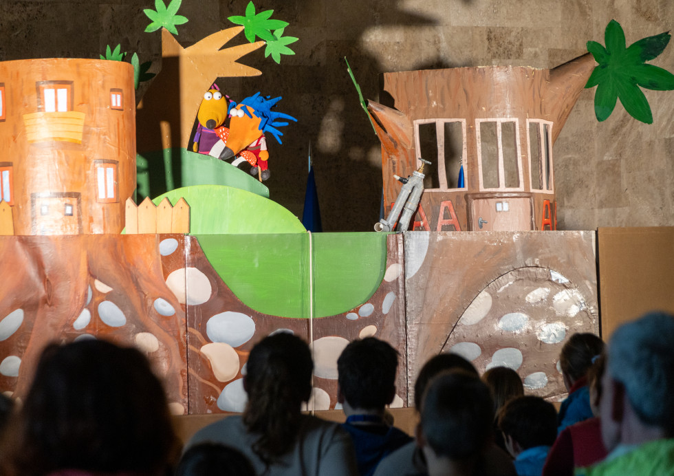 Prizor z lutkovne predstave. Na odru je gasilko Jež in Pikec Ježek. V ospredju so otroci. 