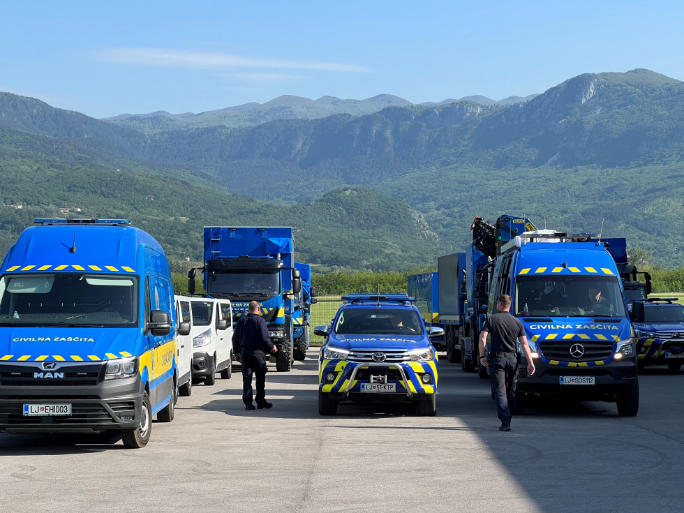 Blue vehicles in front, at the back mountains.