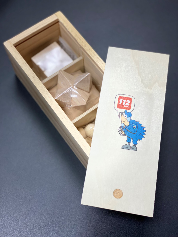 Škatla s tremi različnimi lesenimi miselnimi igrami. Na pokrovu od škatle je ježek in logotip številke 112.