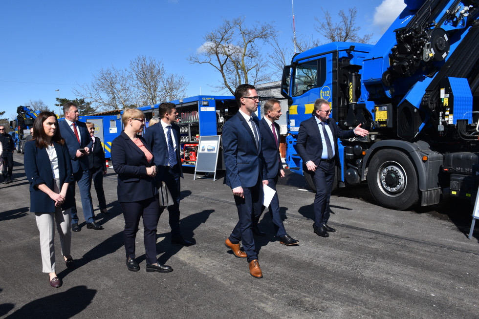 People walking past trucks in blue color.