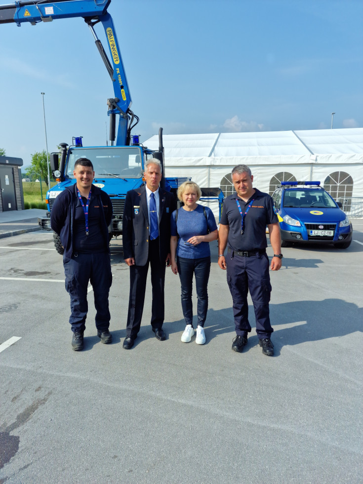 V ospredju z leve proti desni Dejan Sarčević, Sandi Curk, Olga Doles in Matej Nared, na parkirišču v ozadju bel šotor in vozila civilne zaščite.