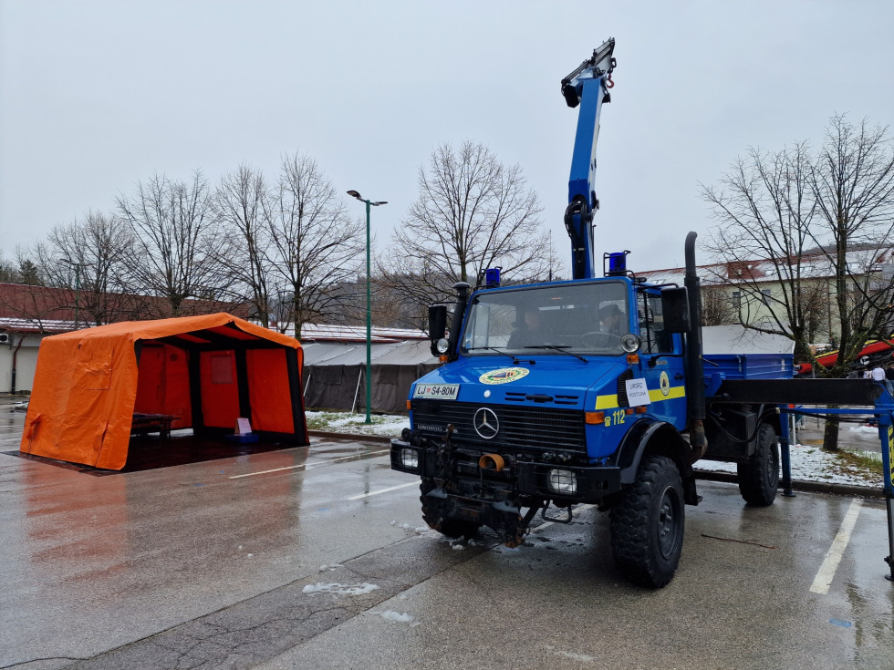 Oranžen šotor in vozilo modre barve z oznako civilne zaščite.