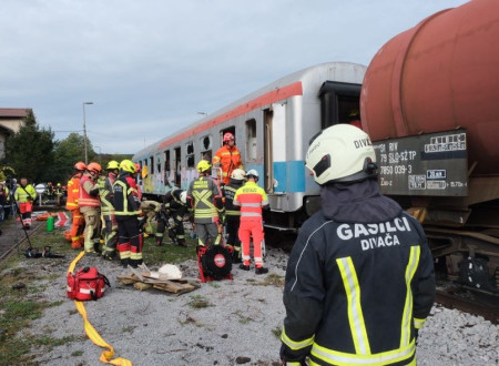 reševalci in gasilci, ki na nosilih prenašajo ponesrečenca iz vlaka