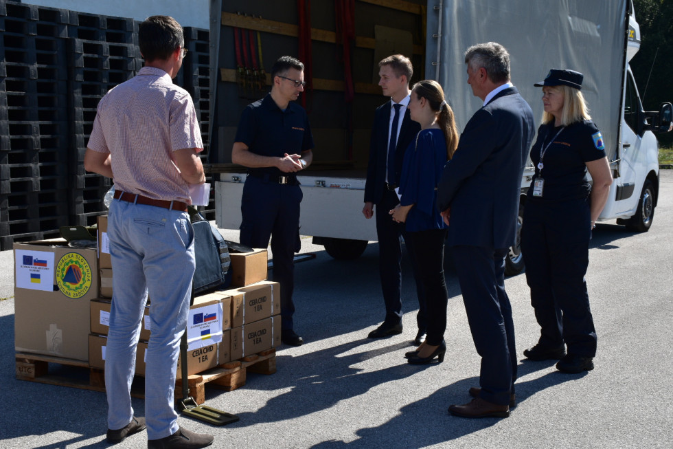 Naštete osebe stojijo v polkrogu zraven razstavljene opreme in pred tovornjakom.