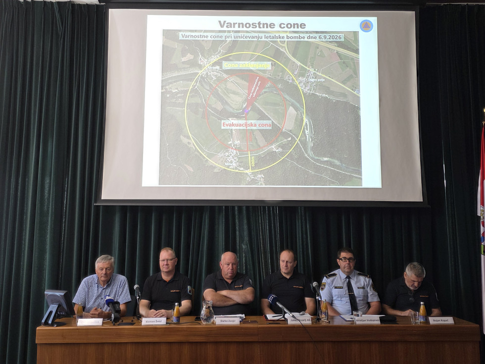 Spodaj sodelujoči na novinarski konferenci, zgoraj projekcija slike na platno.