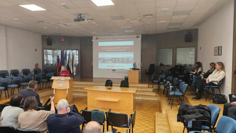 Dvorana posveta, v ozadju platno, v ospredju govornica in udeleženci