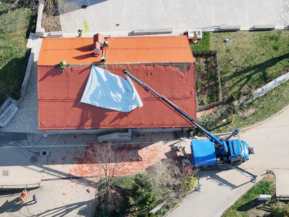 Gasilci prekrivajo streho s platnom.