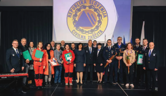 Navzoči posamezniki, prejemniki priznanj različnih organizacij, ki stojijo na odru.