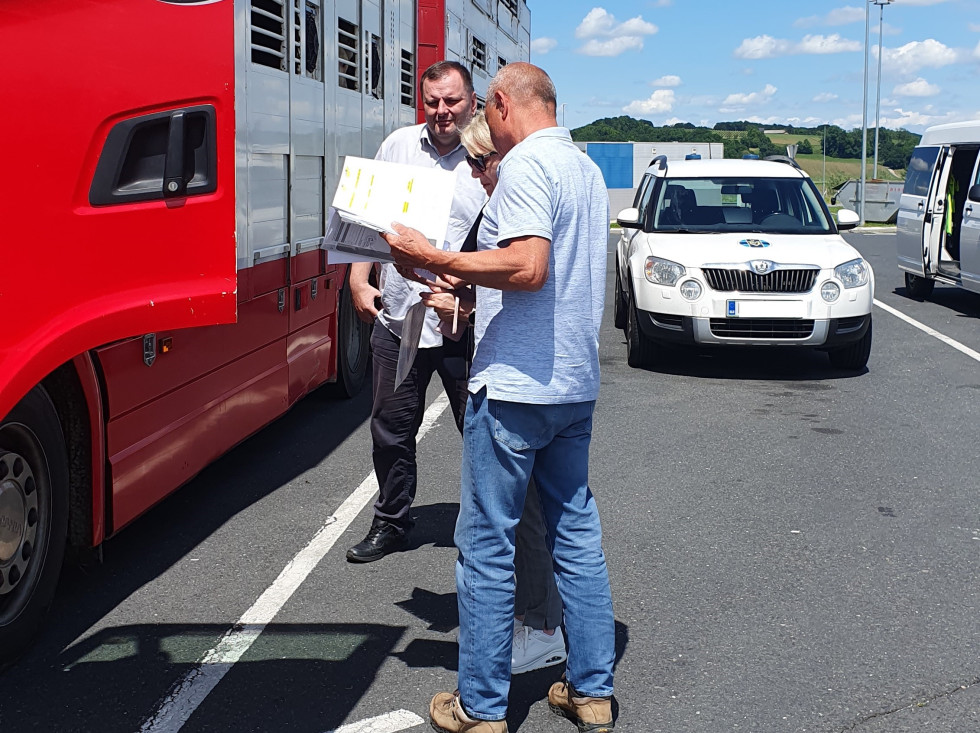 Inpšektoriji stojijo pred kamionom na parkirišču in pregledujejo papirje