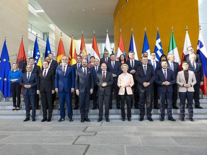 Voditelji in voditeljice držav Berlinskega procesa na skupinski fotografiji v uradu nemškega kanclerja stojijo na stopnišču. Za njimi zastave sodelujočih držav.
