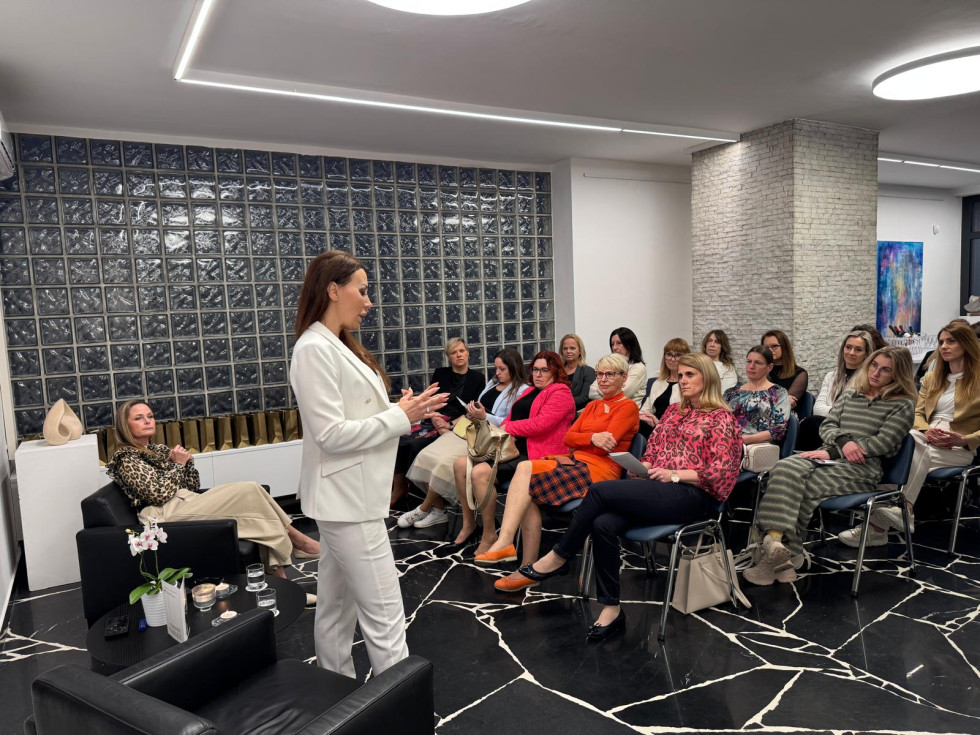 skupina žensk sedi in posluša predavateljico