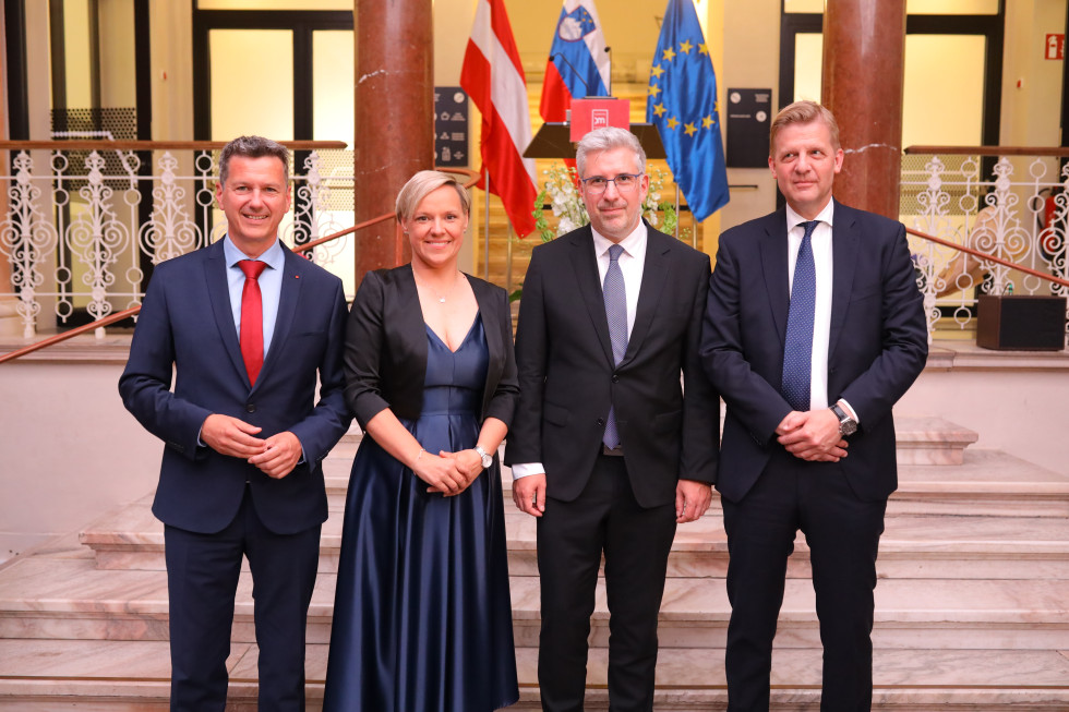štiri osebe se fotografirajo v ozadju zastave