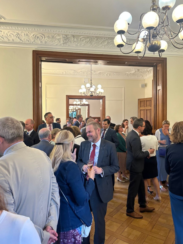 The picture shows a large room full of people attending the reception.